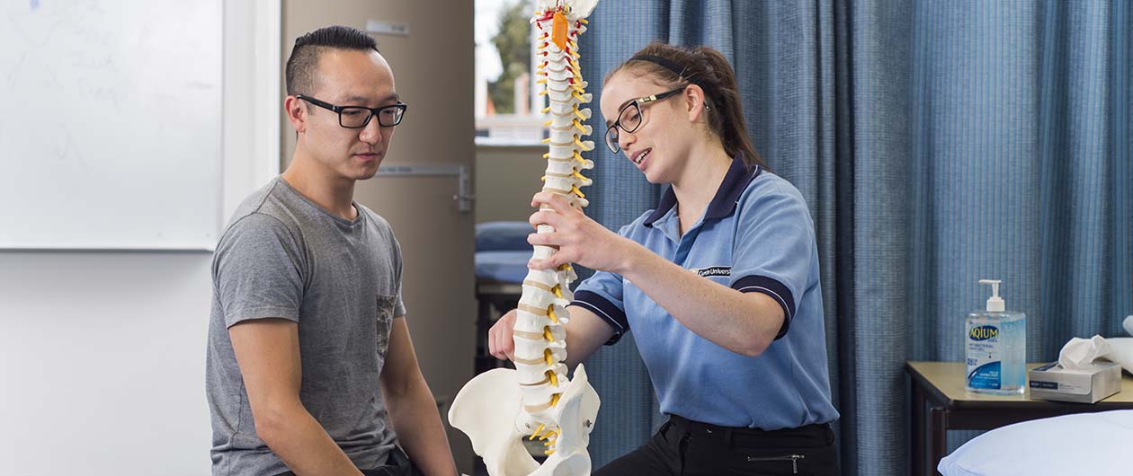 Physio student with client and model of skeleton